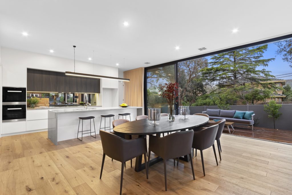 Bright kitchen and dining area with ceiling to floor windows.