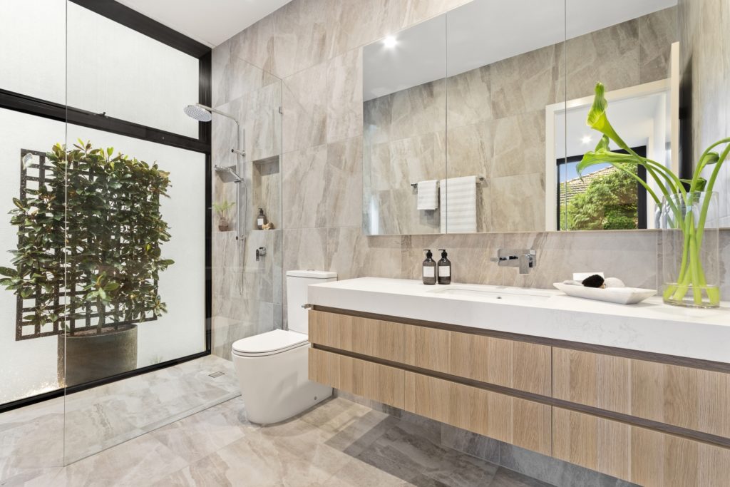 Elegant marble bathroom with modern shower and plants.
