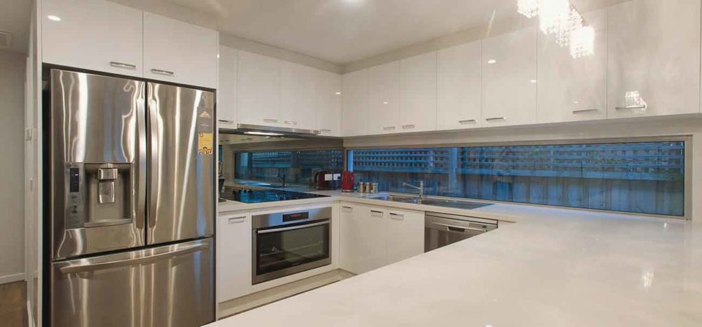 Roomy kitchen with modern fittings and marble benchtop by Mass Constructions.