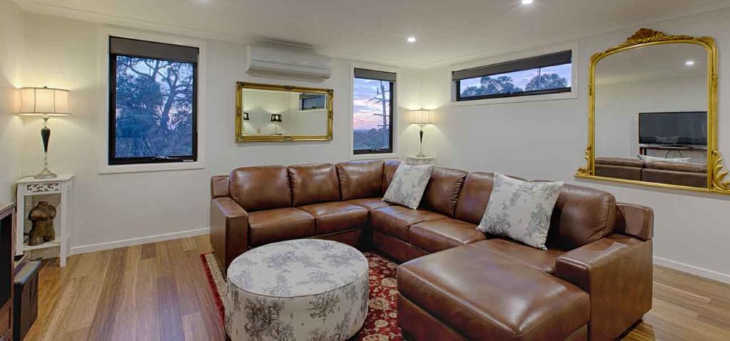 Opulent lounge room with leather chairs, gold mirror and timber floors in Ferntree Gully.