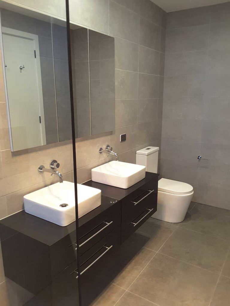 Modern bathroom and toilet with large mirror and twin vanity by Mass Constructions. Location, Glen Iris.