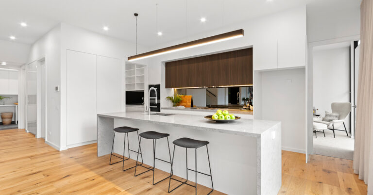 Modern white kitchen with wooden floor.